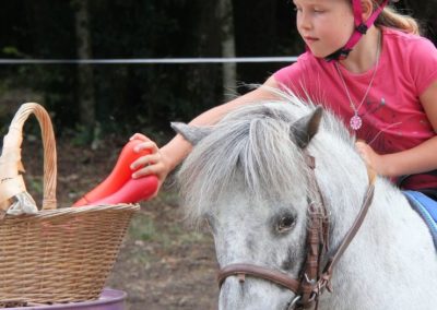 petite fille prend un objet sur son poney